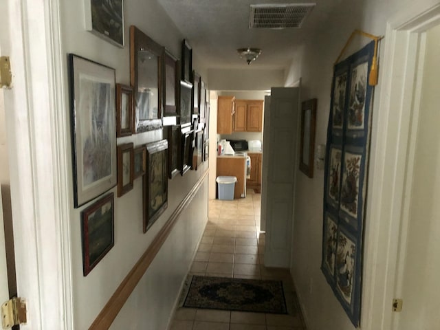 hall featuring visible vents and light tile patterned flooring