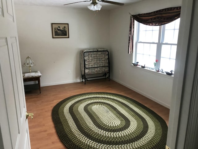 sitting room with light wood finished floors, a ceiling fan, and baseboards