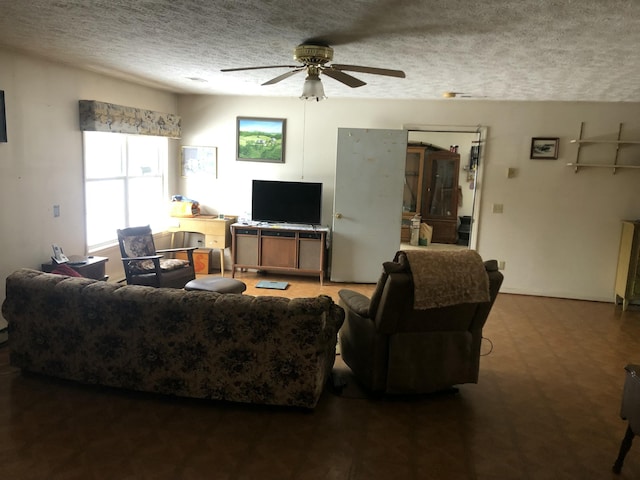 living area featuring dark floors, a ceiling fan, and a textured ceiling