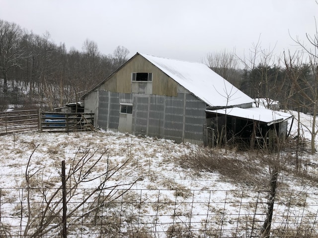 snow covered structure with an outbuilding and fence