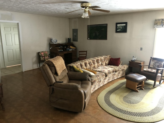 living area featuring a ceiling fan, electric panel, and a textured ceiling