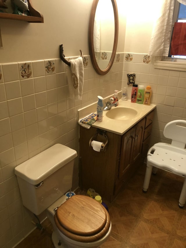 bathroom with toilet, tile walls, and vanity