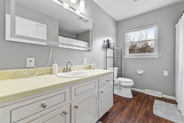 bathroom with toilet, wood finished floors, vanity, visible vents, and baseboards