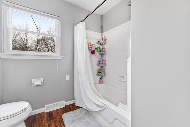 bathroom with toilet, wood finished floors, visible vents, baseboards, and shower / bath combination with curtain