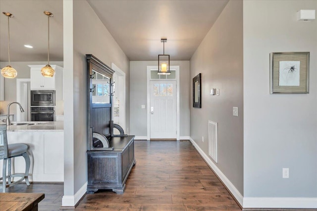 entryway with dark wood-type flooring, visible vents, and baseboards