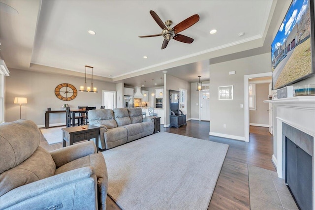 living room featuring a fireplace with flush hearth, baseboards, wood finished floors, and recessed lighting