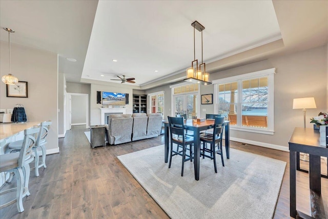 dining room featuring a tray ceiling, dark wood-style flooring, and a fireplace