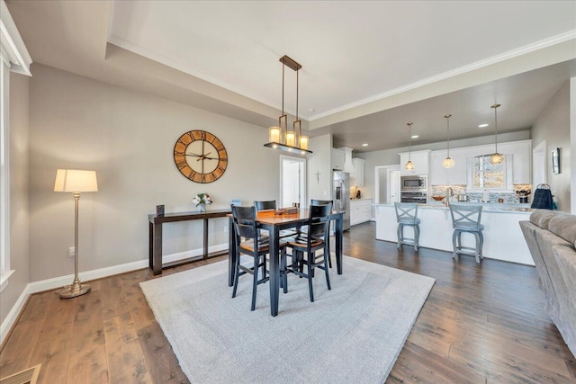 dining room with dark wood-type flooring, a tray ceiling, visible vents, and baseboards