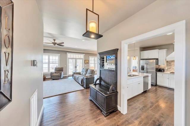 kitchen featuring appliances with stainless steel finishes, dark wood-type flooring, open floor plan, white cabinetry, and a sink