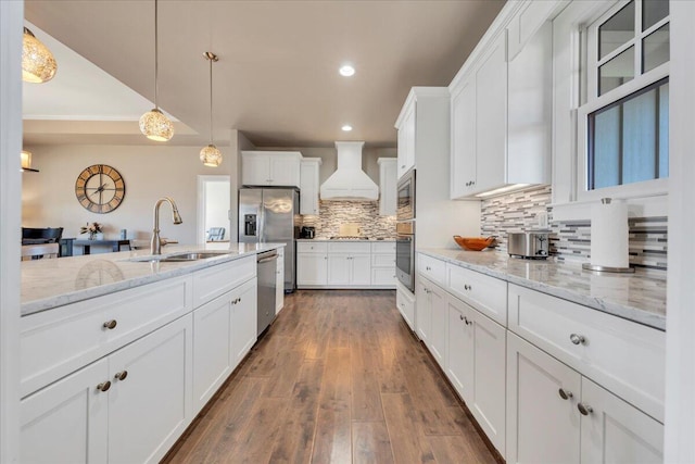 kitchen featuring appliances with stainless steel finishes, custom exhaust hood, white cabinets, and a sink