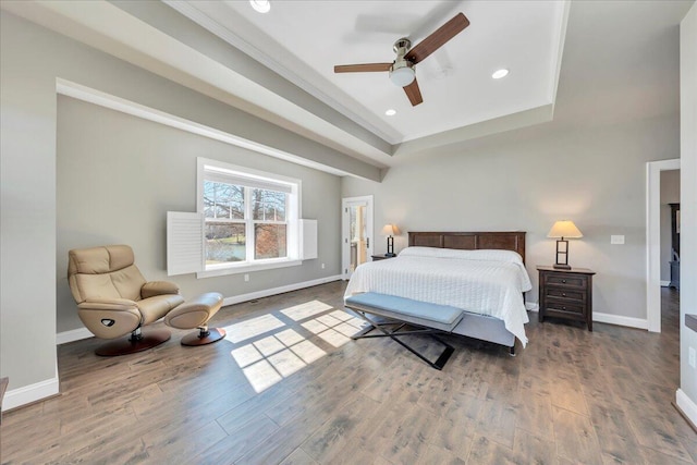 bedroom featuring a raised ceiling, recessed lighting, wood finished floors, and baseboards