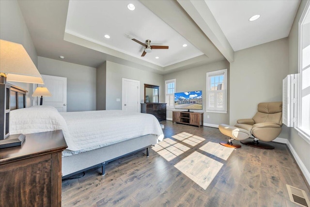 bedroom featuring a raised ceiling, visible vents, baseboards, and wood finished floors