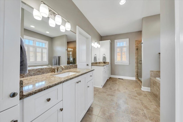 bathroom with baseboards, a stall shower, a sink, and a healthy amount of sunlight