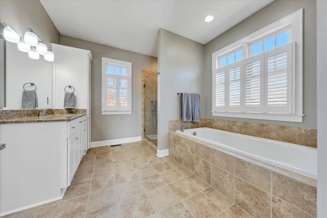 full bathroom with a stall shower, a healthy amount of sunlight, a garden tub, and vanity