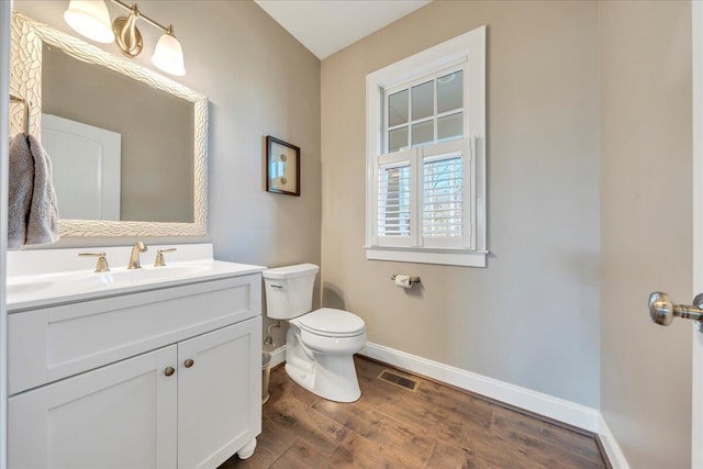 bathroom featuring visible vents, toilet, vanity, wood finished floors, and baseboards