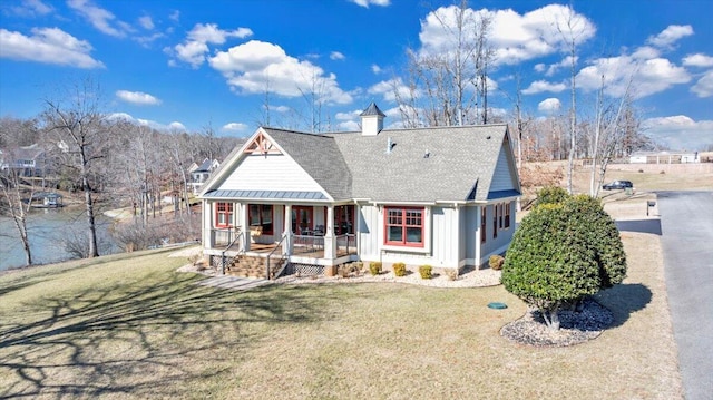 view of front of property featuring roof with shingles, covered porch, a front yard, a standing seam roof, and metal roof