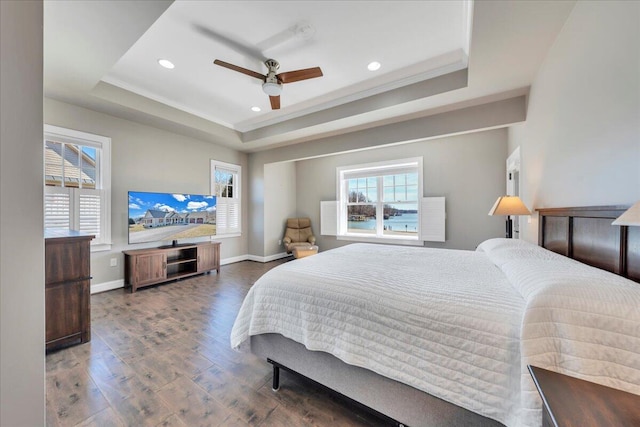 bedroom featuring a raised ceiling, multiple windows, and wood finished floors