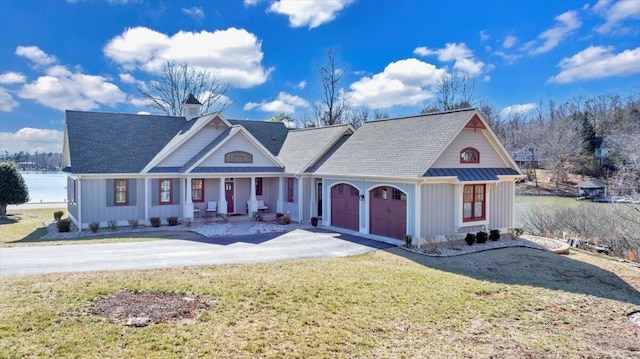 view of front facade featuring metal roof, an attached garage, driveway, a standing seam roof, and a front yard