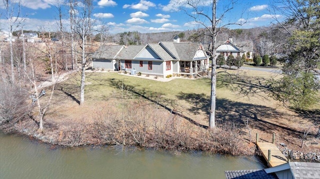 rear view of house featuring a water view, covered porch, and a yard