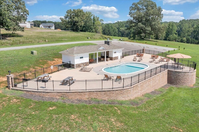 pool with a patio, a yard, and fence