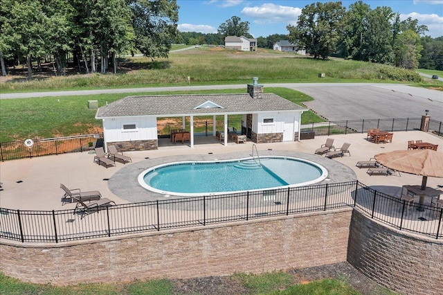 pool featuring a yard, an outbuilding, a patio area, and fence