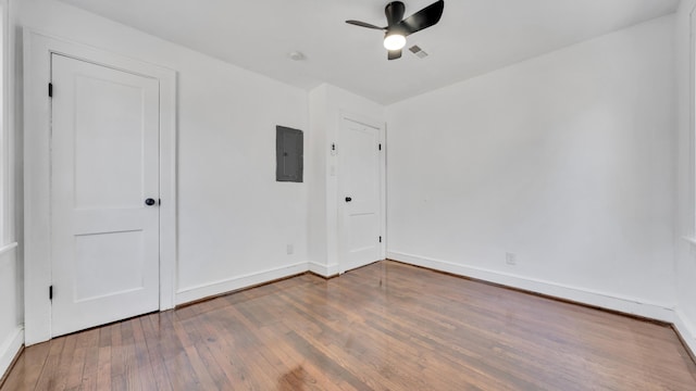 empty room featuring hardwood / wood-style flooring, electric panel, and ceiling fan