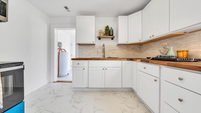 kitchen with tasteful backsplash, butcher block counters, sink, and white cabinets