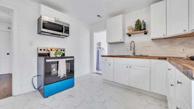 kitchen featuring stainless steel appliances, white cabinetry, butcher block counters, and tasteful backsplash