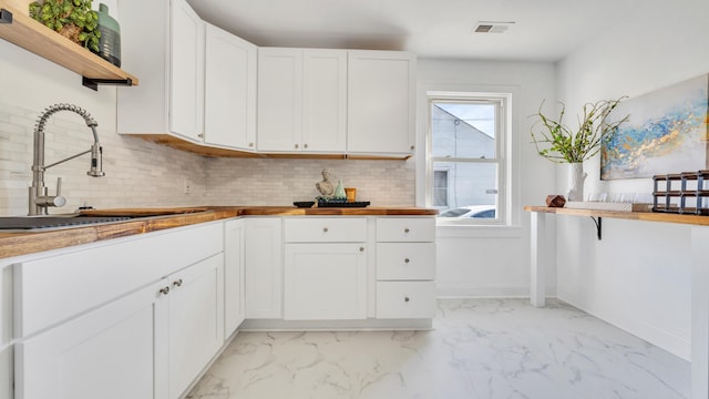 kitchen featuring tasteful backsplash, white cabinetry, and sink