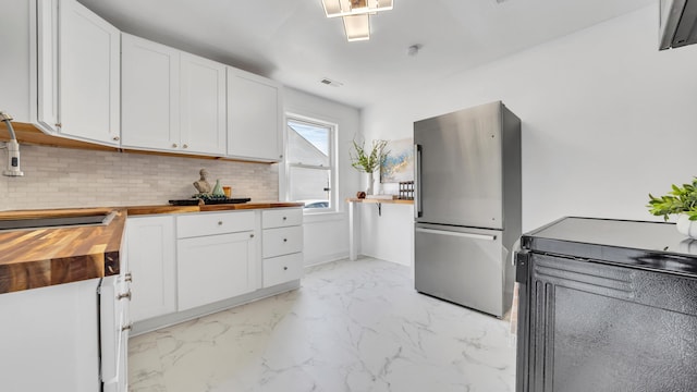 kitchen featuring wood counters, white cabinetry, stainless steel fridge, and decorative backsplash