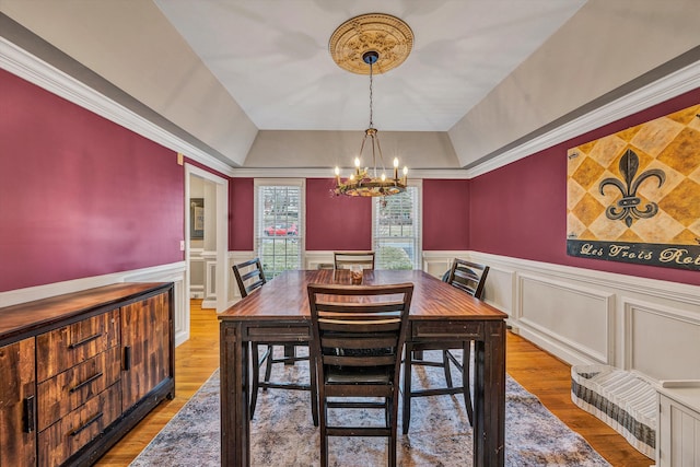 dining room with a wainscoted wall, wood finished floors, and a notable chandelier