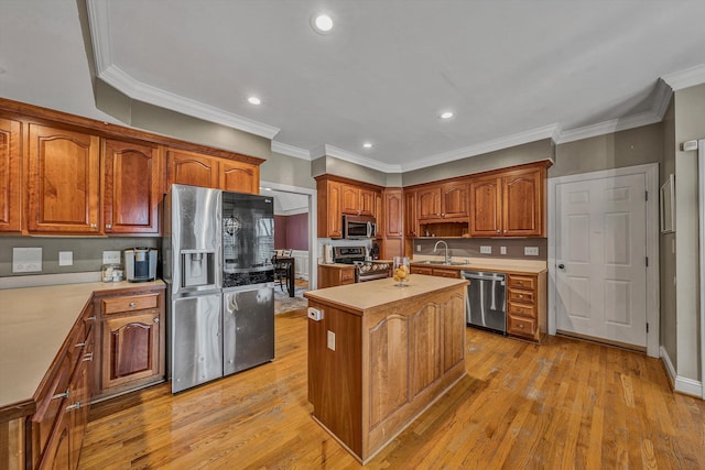 kitchen featuring light countertops, stainless steel appliances, a sink, light wood-type flooring, and a center island