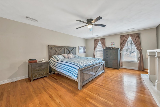 bedroom featuring light wood finished floors, baseboards, visible vents, and a ceiling fan
