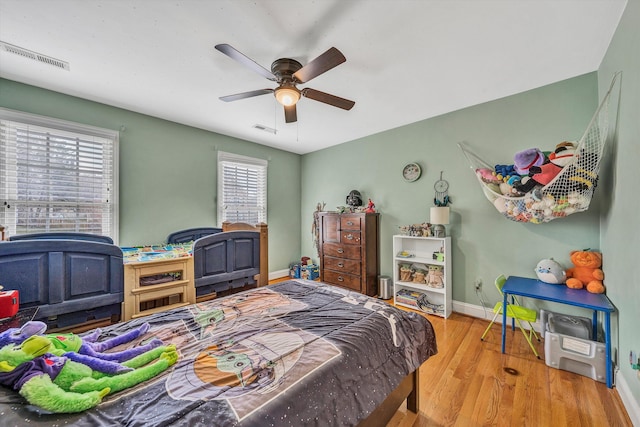 bedroom featuring a ceiling fan, wood finished floors, baseboards, and visible vents