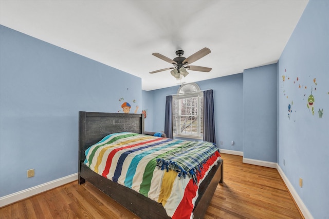 bedroom featuring baseboards, wood finished floors, and a ceiling fan