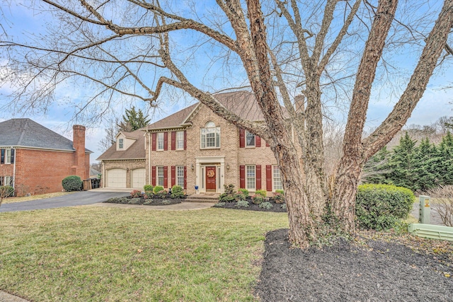 view of front facade featuring a garage, a front yard, aphalt driveway, and brick siding