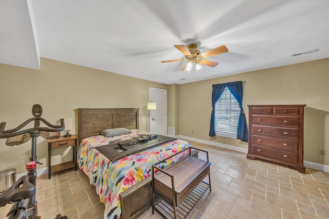 bedroom with stone finish floor, baseboards, visible vents, and a ceiling fan