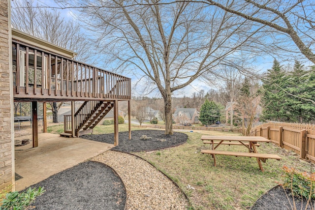 view of yard featuring a deck, stairway, fence, and a patio