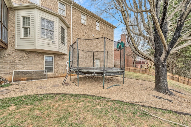 view of yard featuring a trampoline and fence