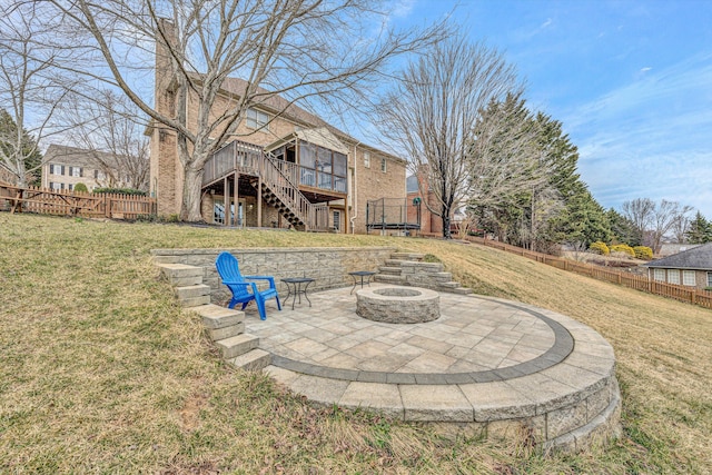 back of house featuring stairs, an outdoor fire pit, a trampoline, a patio area, and a lawn