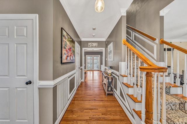 corridor with ornamental molding, wood finished floors, and stairway