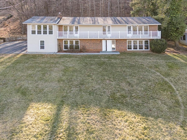 view of property featuring brick siding, a chimney, and a front lawn