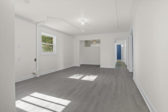 empty room featuring wood finished floors, attic access, and baseboards