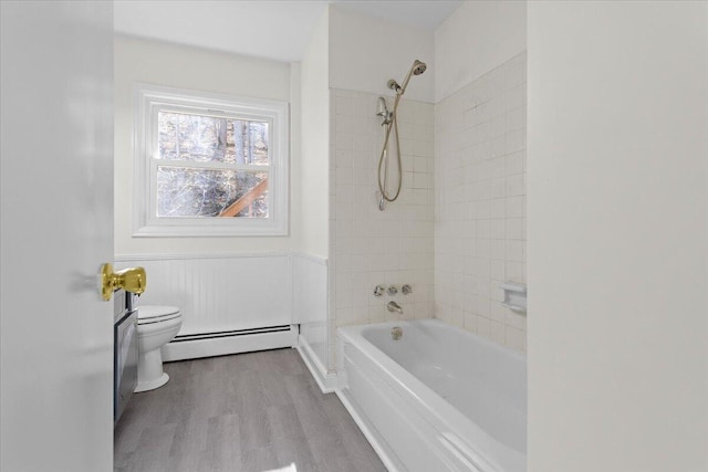 bathroom with a wainscoted wall, shower / bath combination, toilet, baseboard heating, and wood finished floors