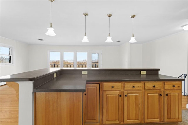 kitchen featuring hanging light fixtures, dark countertops, a kitchen island, and brown cabinets