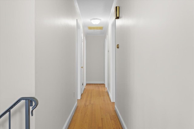 hall featuring light wood-style floors, visible vents, and baseboards