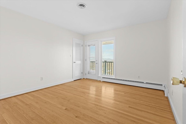 empty room featuring baseboards, visible vents, light wood finished floors, and baseboard heating