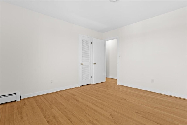 unfurnished room featuring light wood finished floors, baseboard heating, and baseboards