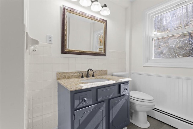 1909 Pelham Dr, Roanoke, VA 24018 - bathroom with vanity, a baseboard heating unit, toilet, a wainscoted wall, and tile walls