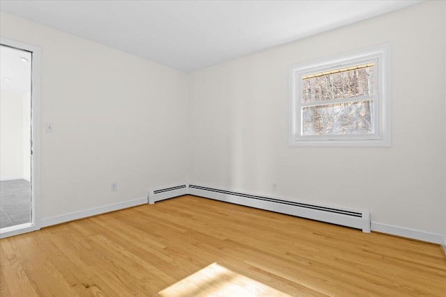 spare room with a baseboard heating unit, wood finished floors, and baseboards